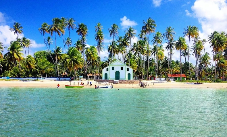 Agua turquesa, playa, palmeras y una pequeña capilla blanca